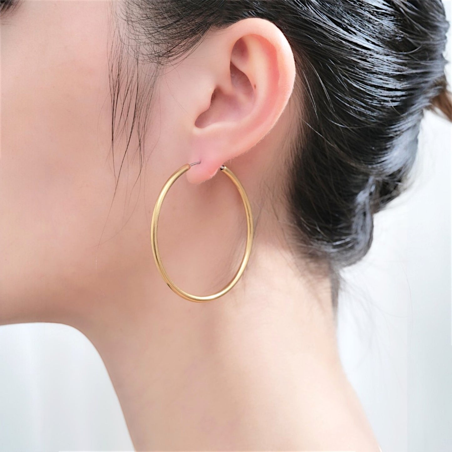 Hoops on a white woman made from titanium. Gold large 45mm titanium earring
