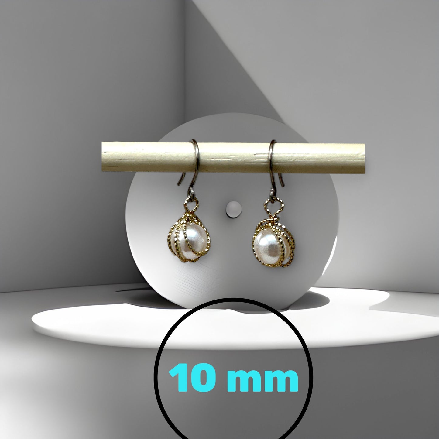 Pair of pearl titanium earrings on a white stand with a measurement label indicating 10 mm.