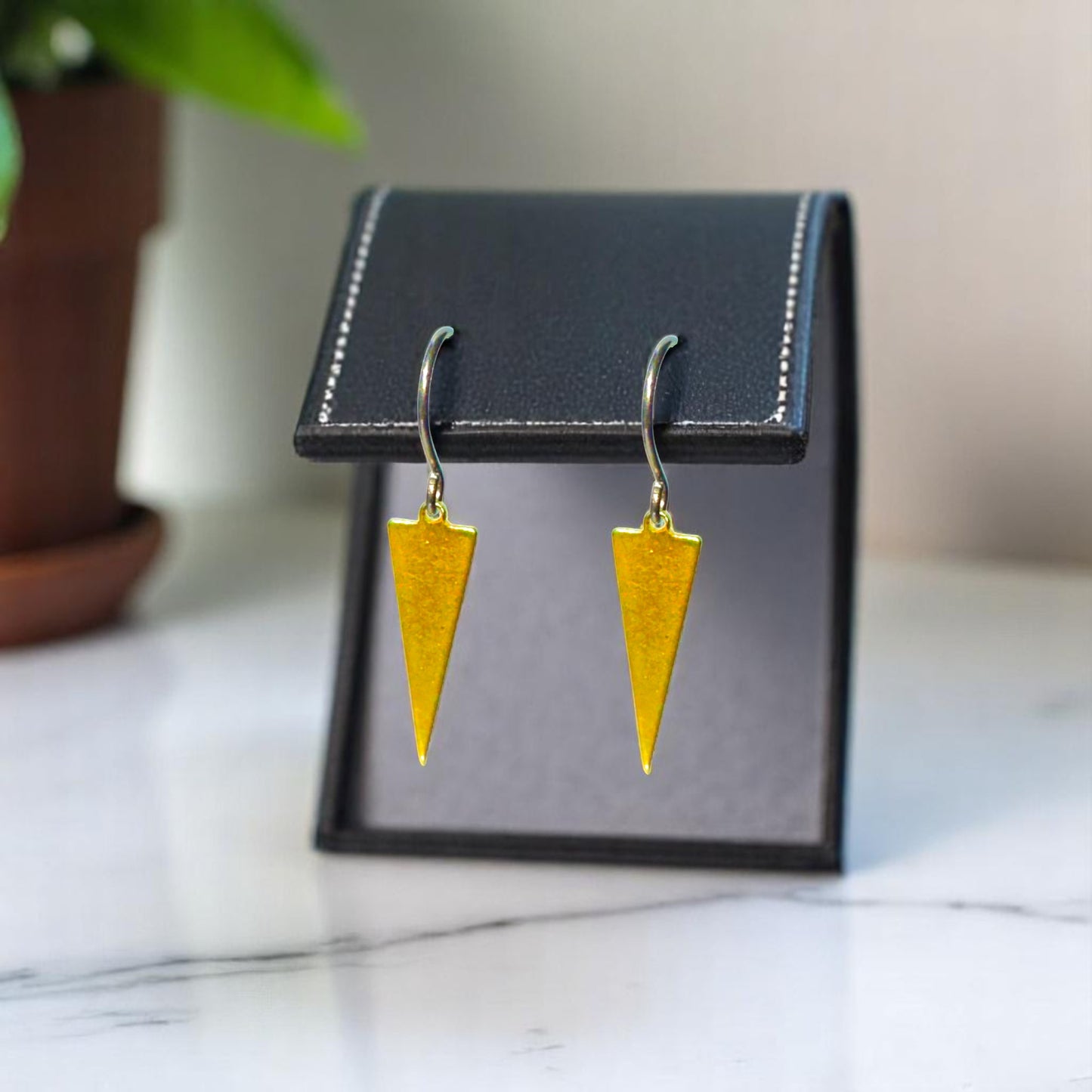 Minimal Narrow Triangle Earrings with a titanium hook on a leather background