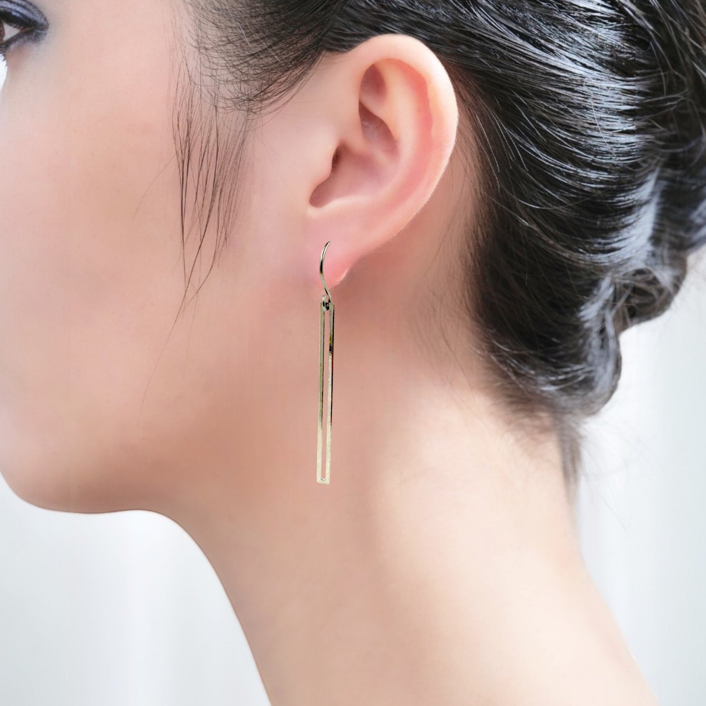 Silver narrow rectangular loop earring with a titanium hook on a white young woman
