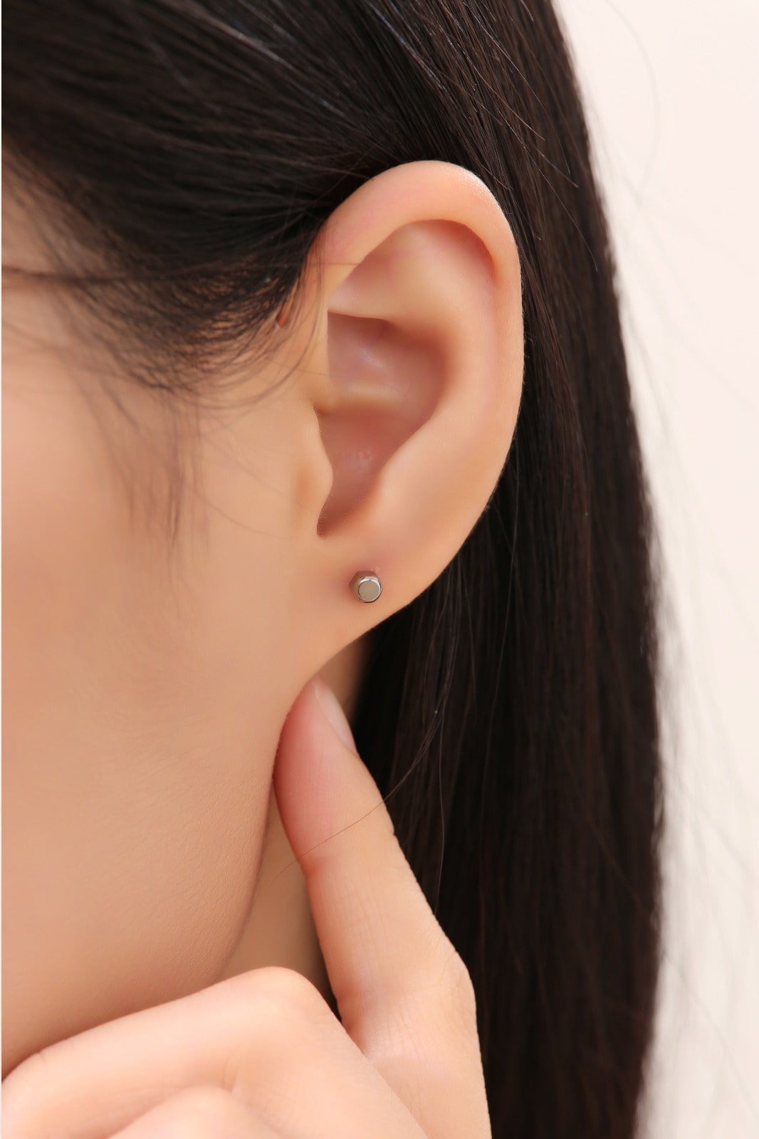 Small Cap Nut Studs -solid titanium studs and backs- Feature a small and minimal design on a white woman.