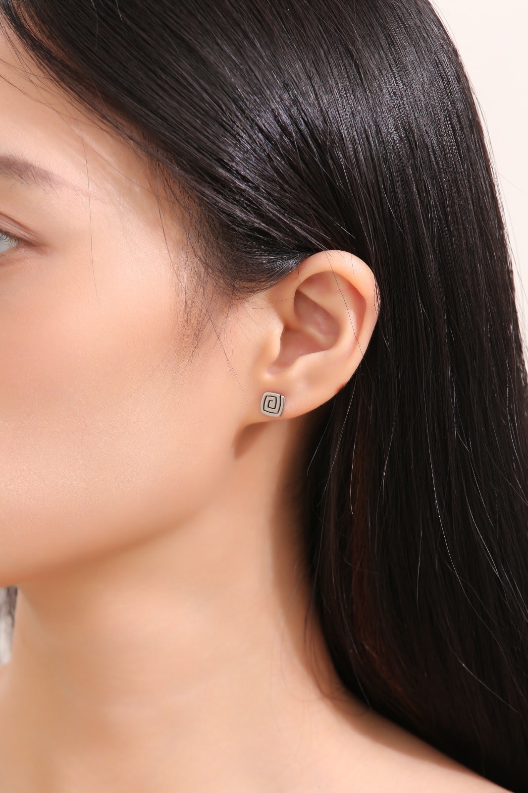 Swirl Titanium Studs -solid titanium studs and backs- Feature a small and minimal design on a white woman.