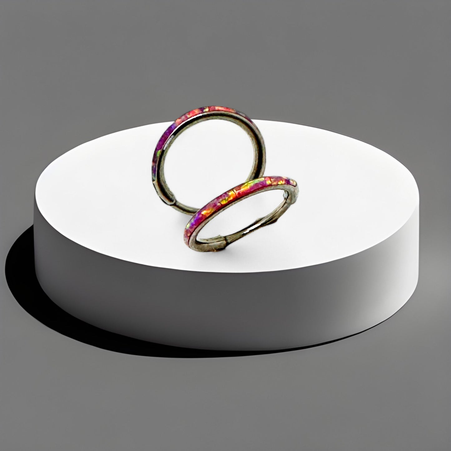 Titanium 8 mm coloured hoops on a white circular stand against a gray background