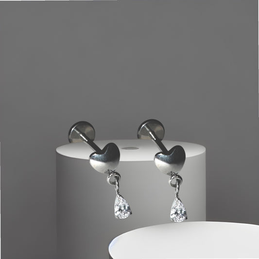 Pair of titanium earrings with heart and teardrop hanging gem on a gray background