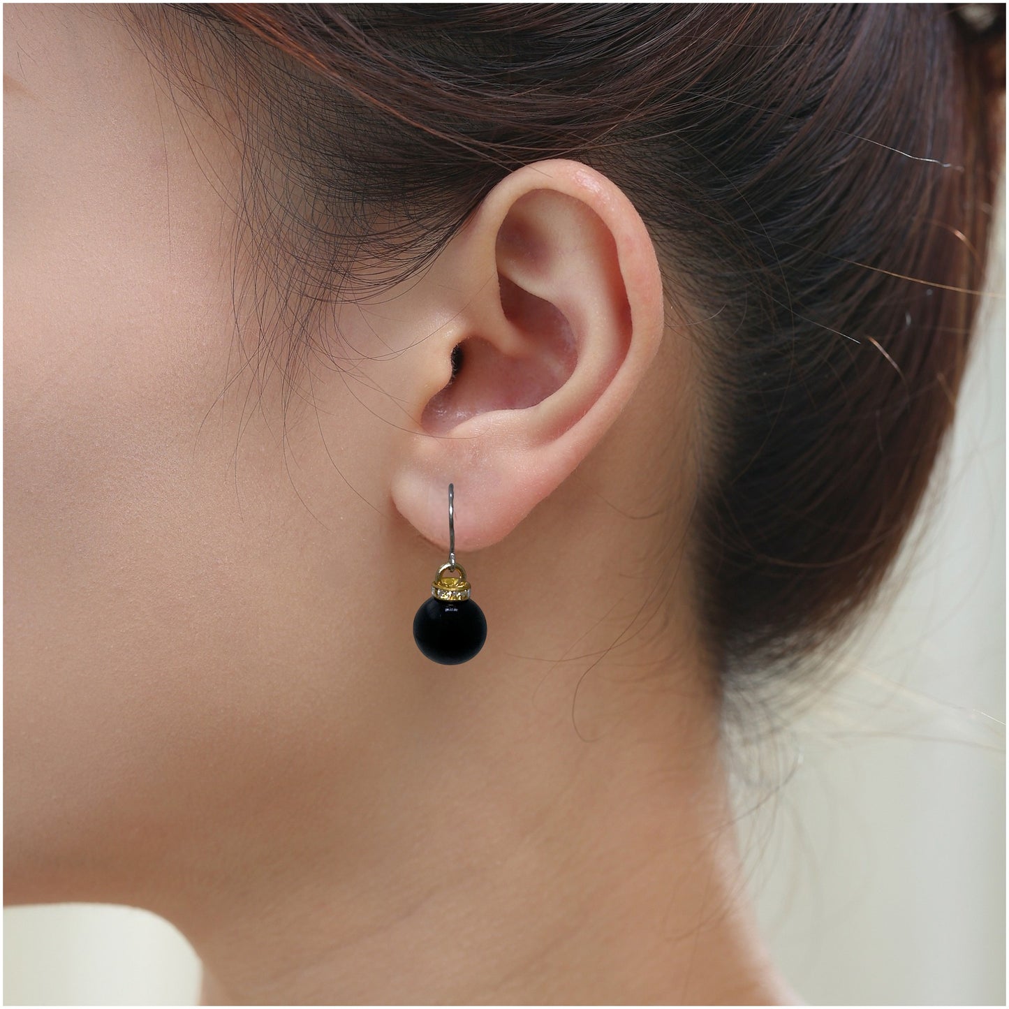 Black pearl earrings with a titanium hook on a white young woman