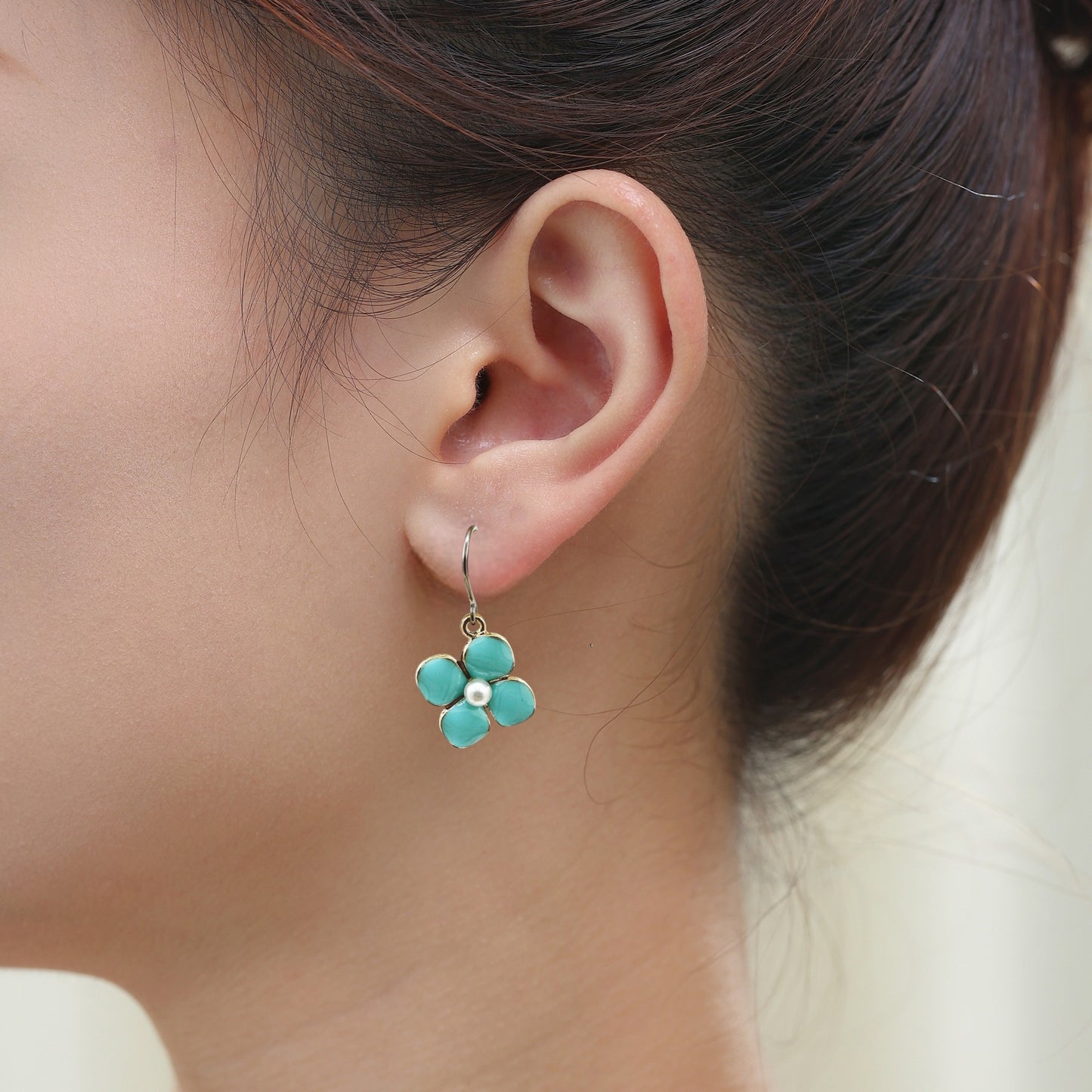 Forget Me Not earrings in blue with a pearl in the center and a titanium hook on a white young woman