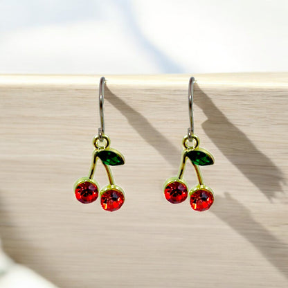 Cherry earrings with a titanium hook on a wood background