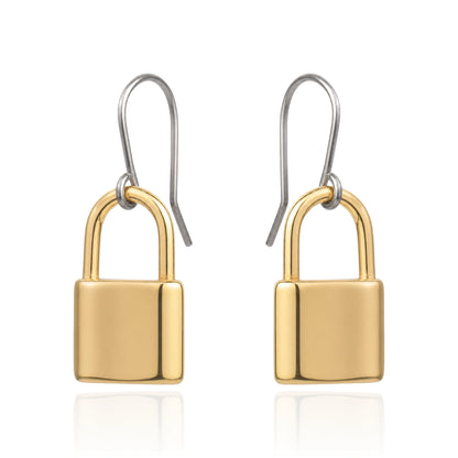 A pair of drop earrings shaped like small padlocks, with polished yellow-gold and titanium hook wires above, shown on a clean white background with a faint reflection below.