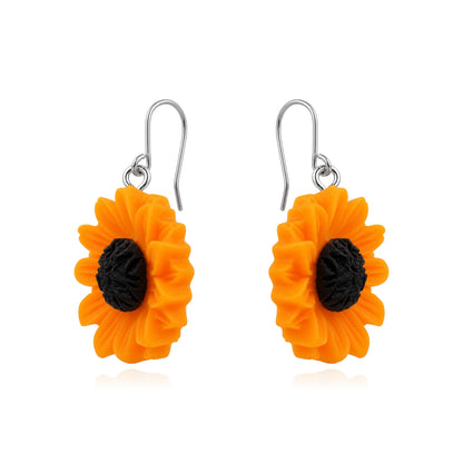 A pair of titanium dangling flower earrings shaped like bright orange sunflowers with textured black centers and titanium fishhook wires, shown on a plain white background.