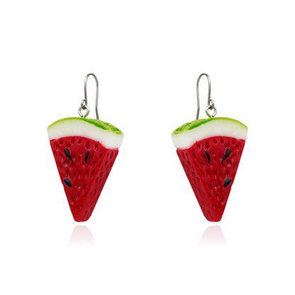 A pair of watermelon slice drop earrings with red bodies, white rinds, green edges, and small black seeds on titanium hooks, shown on a white background.