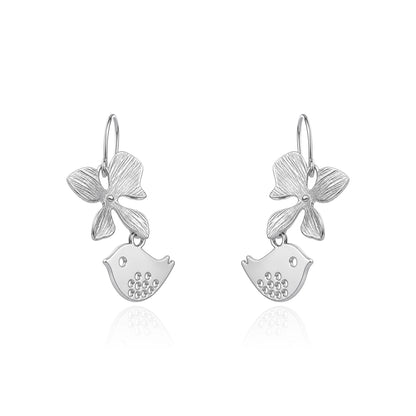 A pair of titanium dangle earrings featuring a textured flower and a small bird charm shown on a white background 