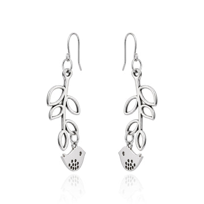 A pair of titanium dangle earrings featuring a leafy vine design with a small bird charm at the bottom, shown on a white background with a soft reflection.