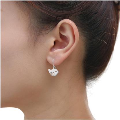 Songbird Charm earrings with a titanium hook on a white young woman. silver bird