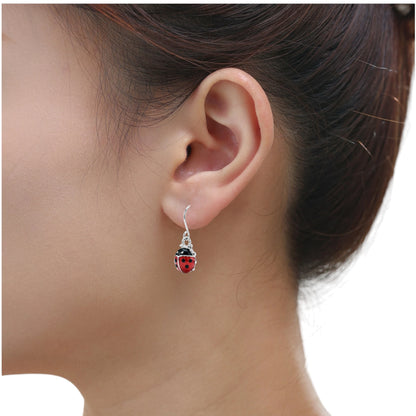 Ladybug earrings with a titanium hook on a white young woman