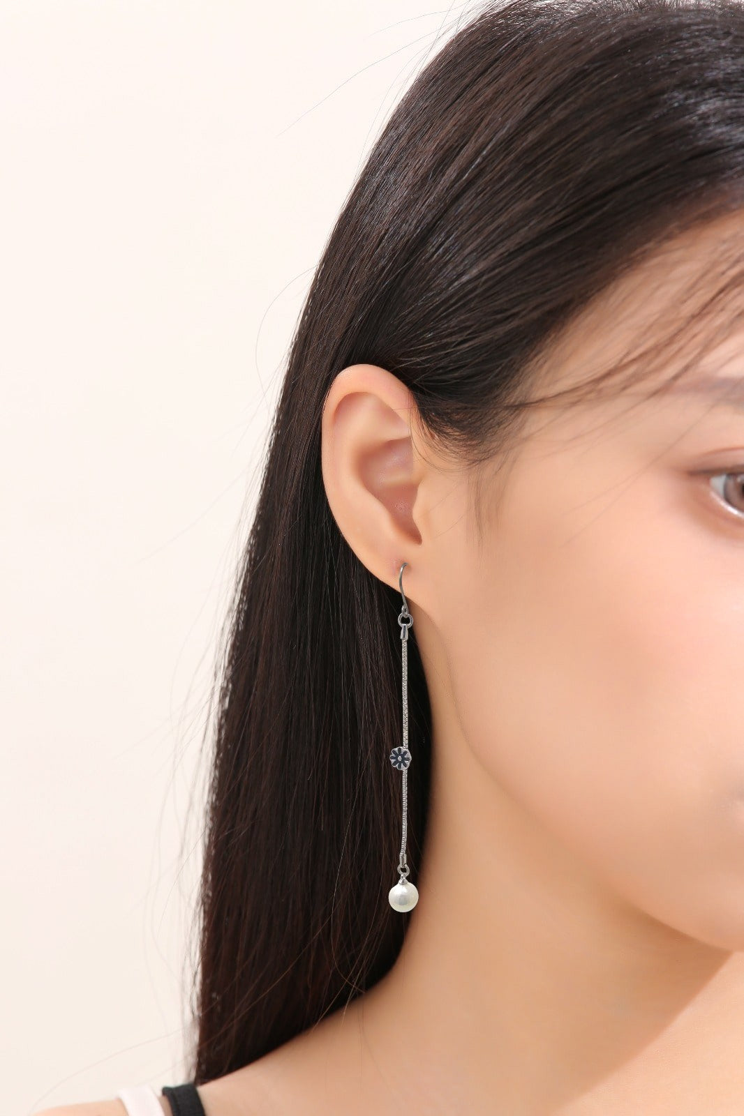 Daisy and Pearl earrings with titanium hooks. This slender silver chain with daisy and pearl is an eye-catching accessory. On a young woman. 