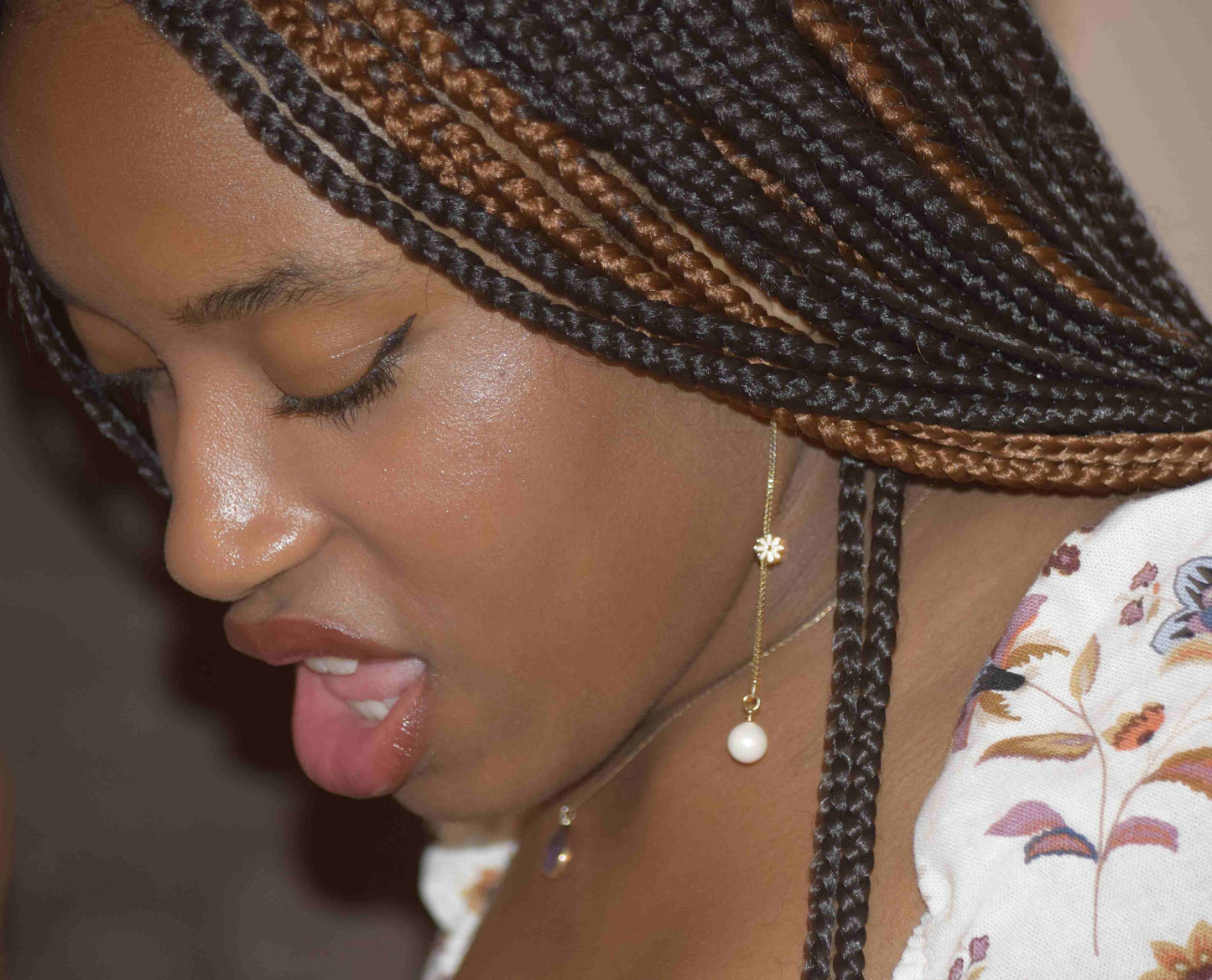 Daisy and Pearl earrings with titanium hooks. This slender gold chain with daisy and pearl is an eye-catching accessory. On a black young woman. 