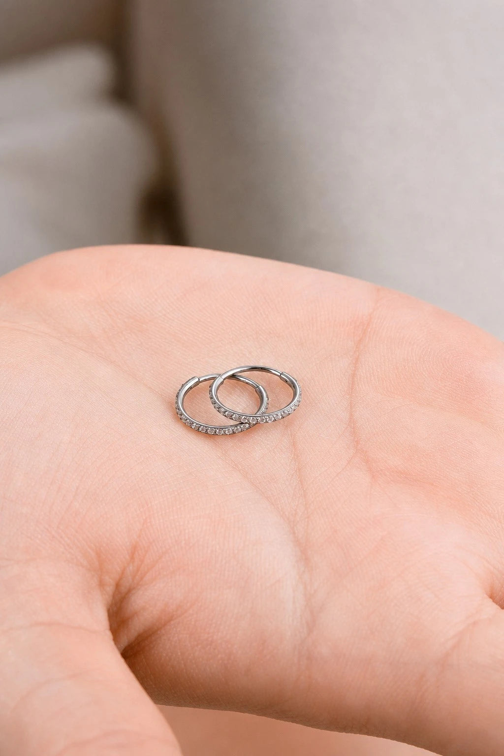 Small diamond Hoop pair earrings made from titanium on a hand.