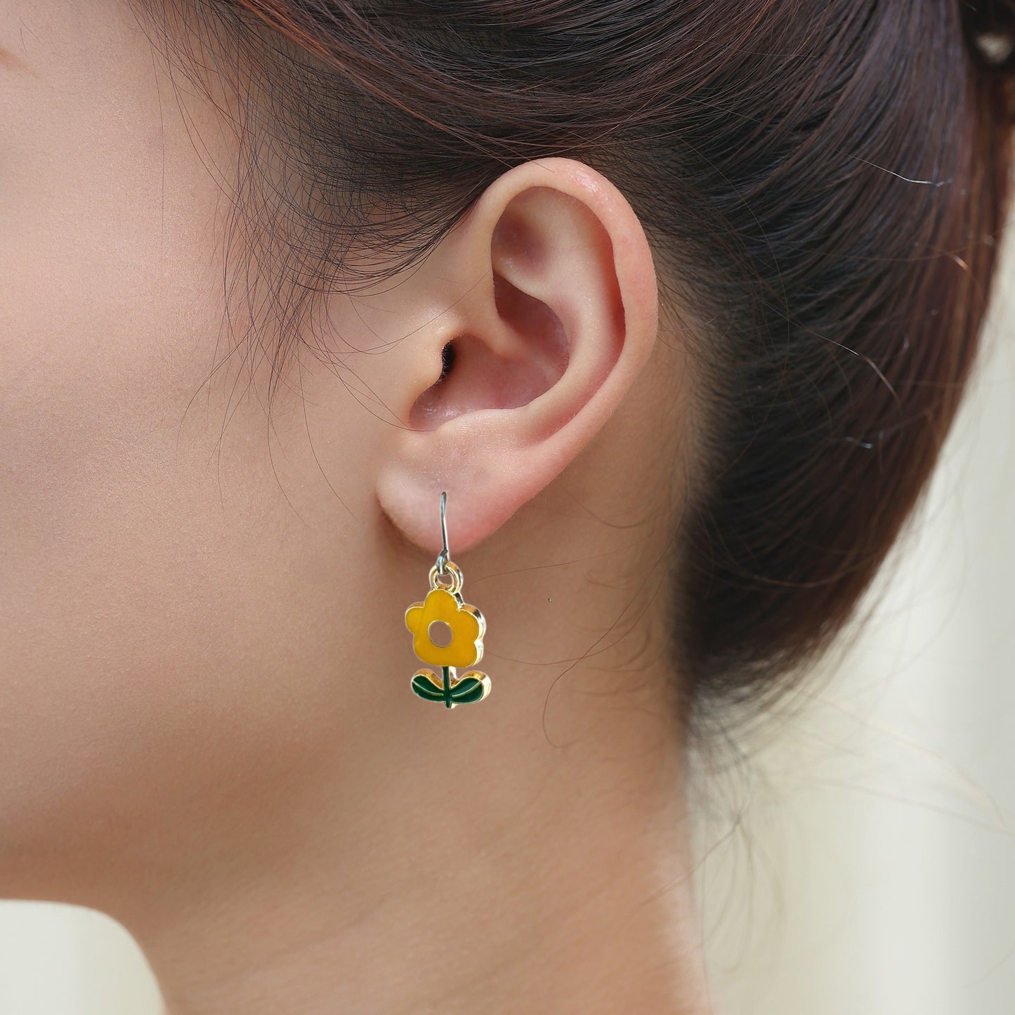 Flower power earrings in yellow with green leaves and a titanium hook on a white young woman