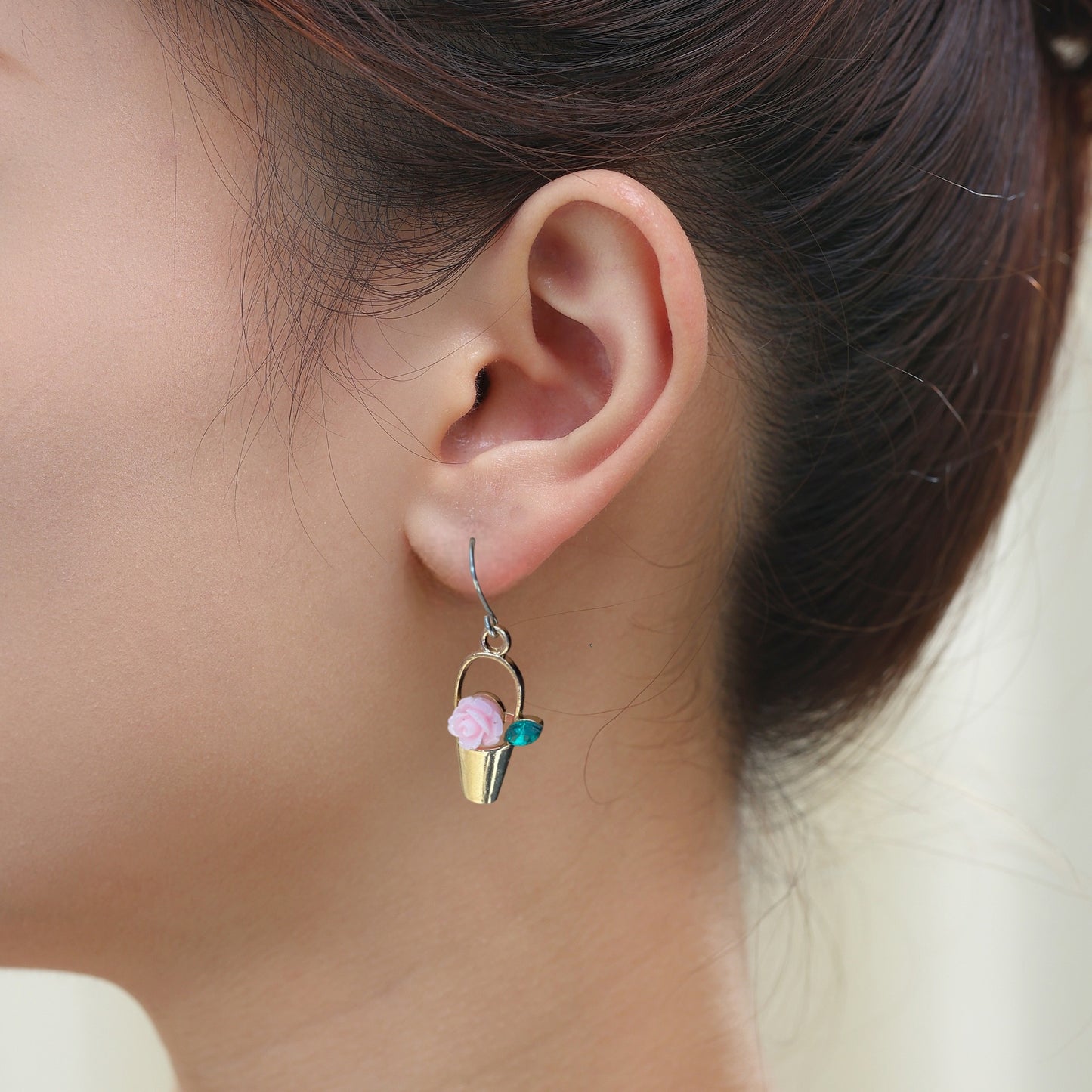 Gardener’s Charm earrings in gold with pink flower and a titanium hook on a white young woman