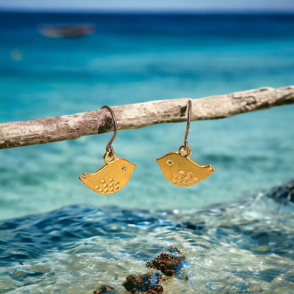 Songbird Charm earrings with a titanium hook on a ocean background