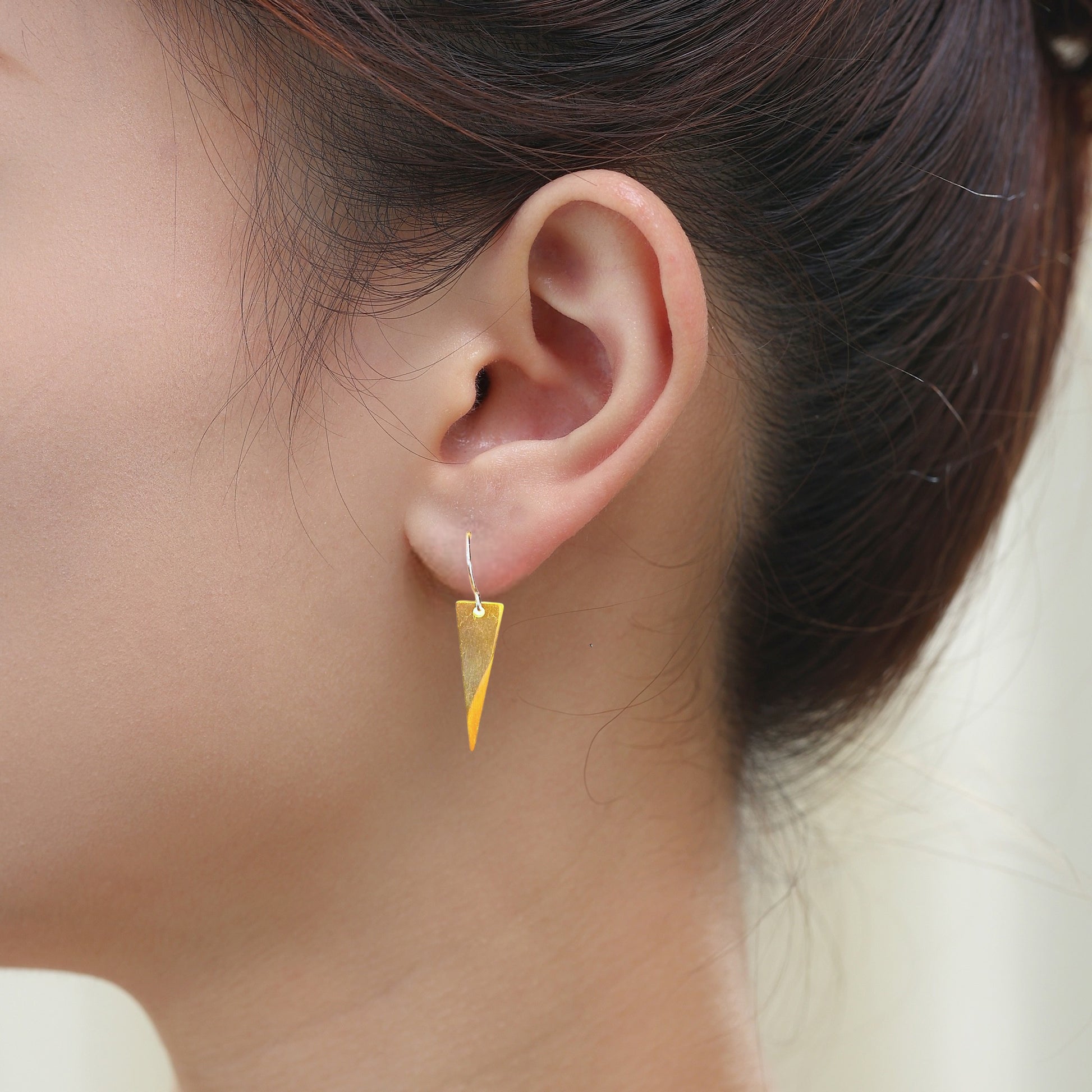 Minimal Narrow Triangle Earrings with a titanium hook on a white young woman