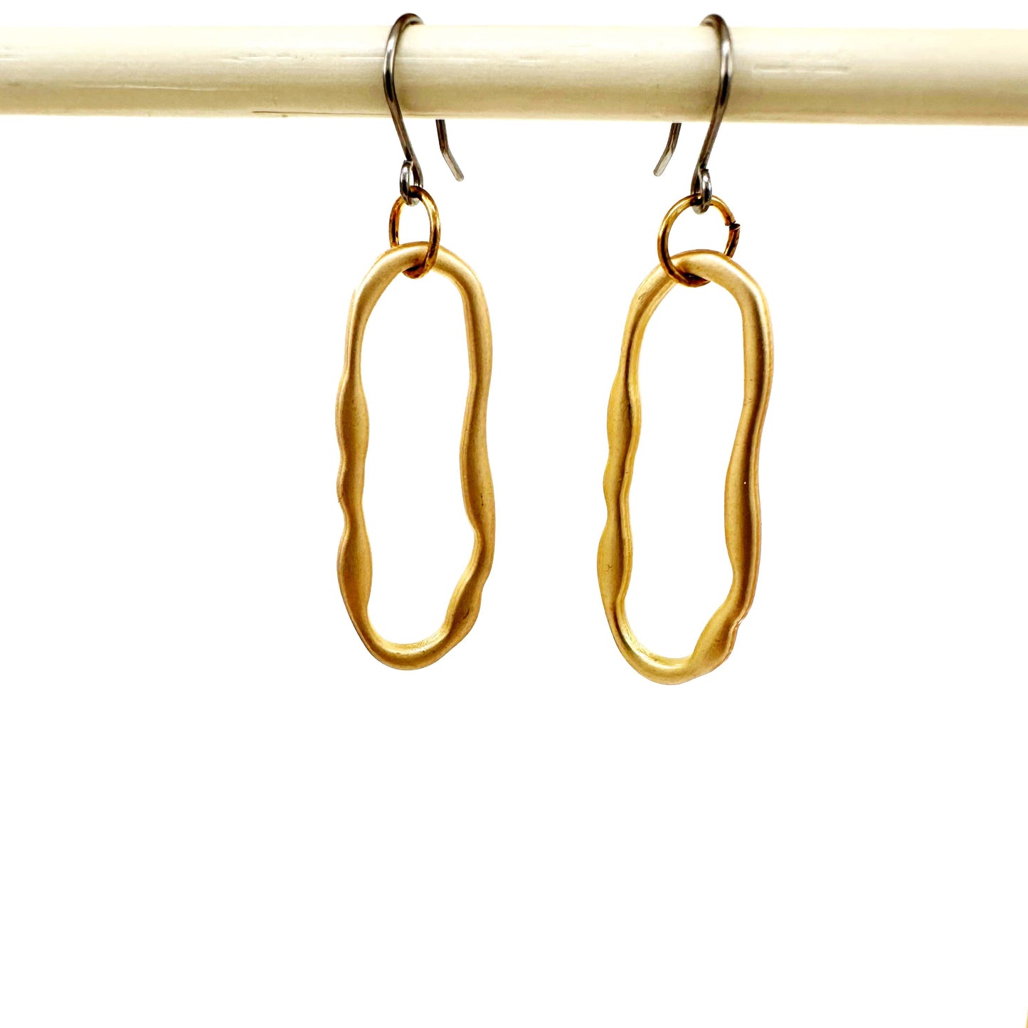 Gold oblong loop medium size earrings with a titanium hook on a white background