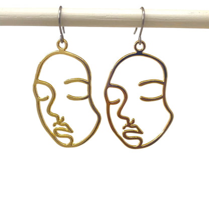 Golden face drop earrings with a titanium hook on a white background