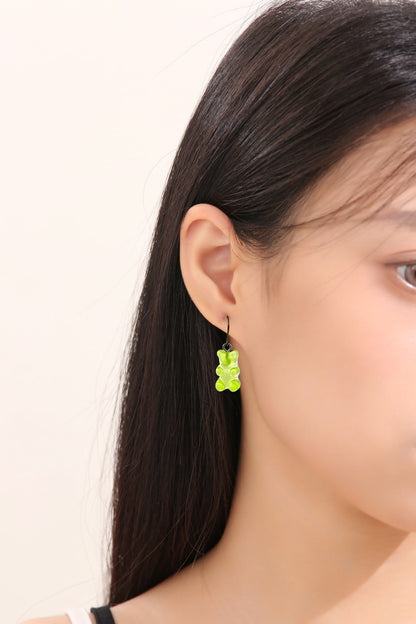 Gummy bear earrings with a titanium hook on a white young woman. green