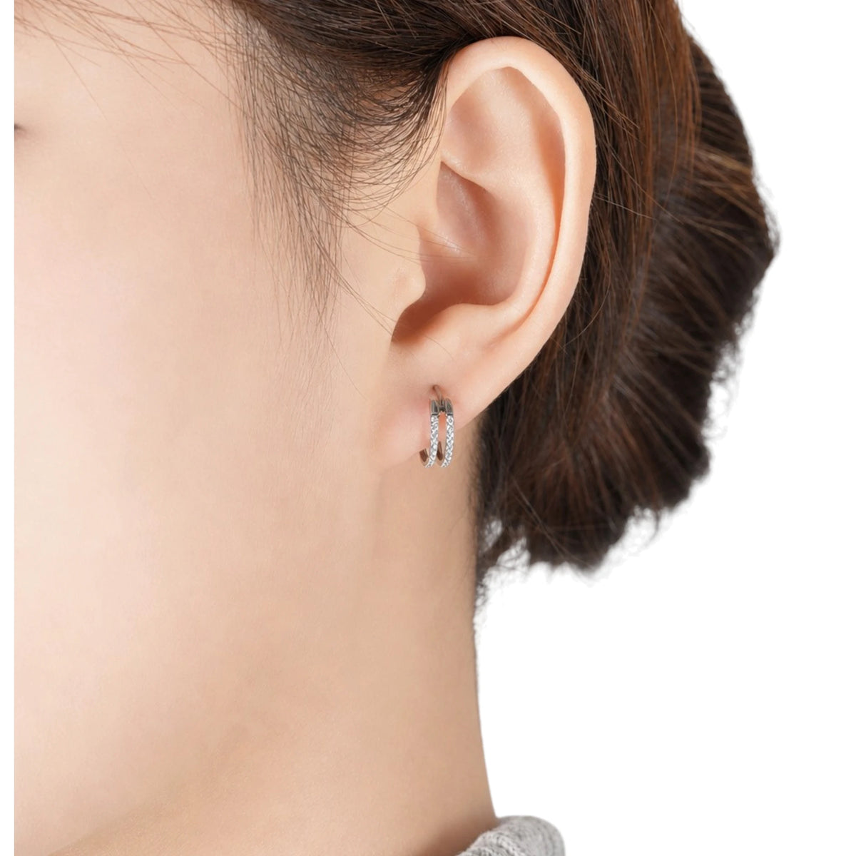 A close-up of a person's ear wearing a titanium small round-shaped hoop earring with diamond gems around both hoops.