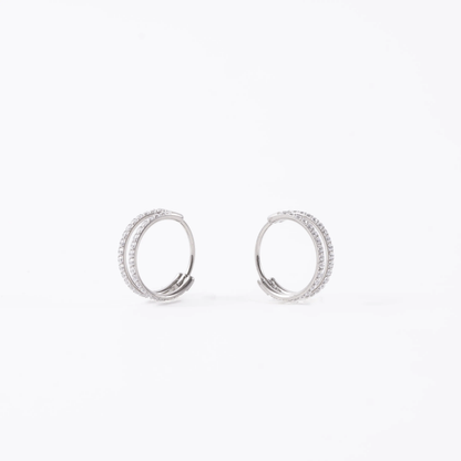 A pair of titanium double hoop earrings adorned with clear pavé-set round diamond gems, shown against a plain white background.