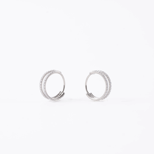 A pair of titanium double hoop earrings adorned with clear pavé-set round diamond gems, shown against a plain white background.