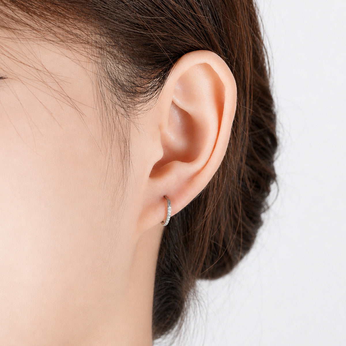 Small Hoop diamond earrings made from titanium on a white woman gem studded earring. 