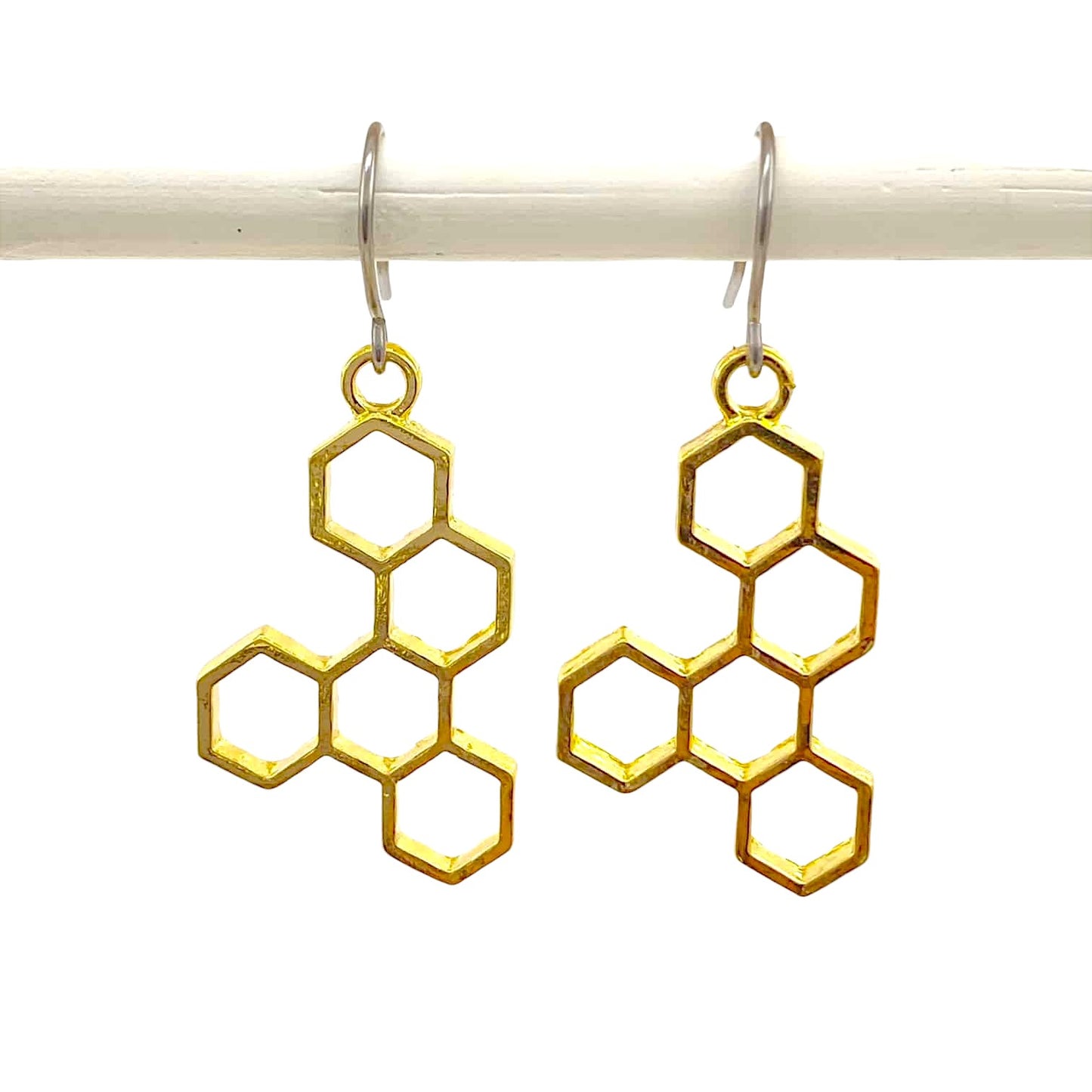 Honeycomb gold earring with a titanium hook on a white background