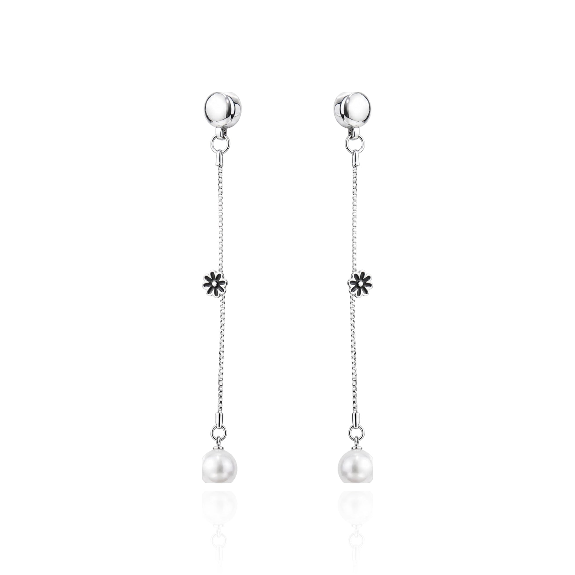 A pair of ti-go titanium interchangeable magnetic dangle earrings with a small flower charm and a white pearl drop, shown on a clean white background with a subtle reflection.