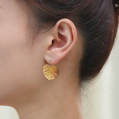 Large Monstera Leaf Earrings with a titanium hook on a white young woman