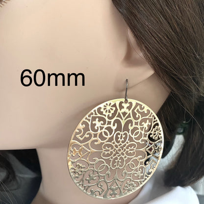 Gold Geometric disc earrings 60mm diameter with a titanium hook on a white young woman.