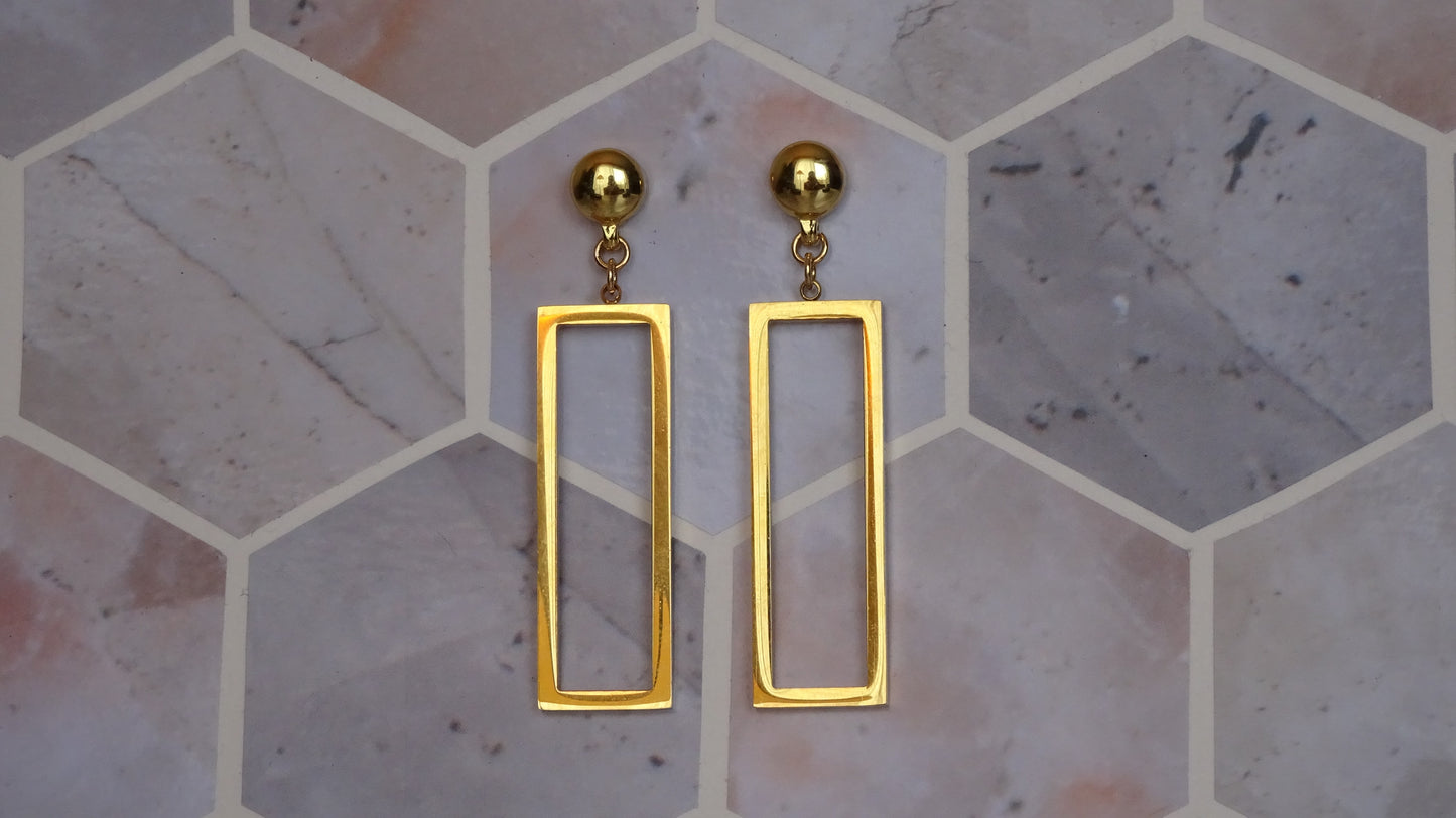 Magnetic-Rectangle mirrored gold earrings. Detachable earrings for a truly hypoallergenic jewellery on a tile background