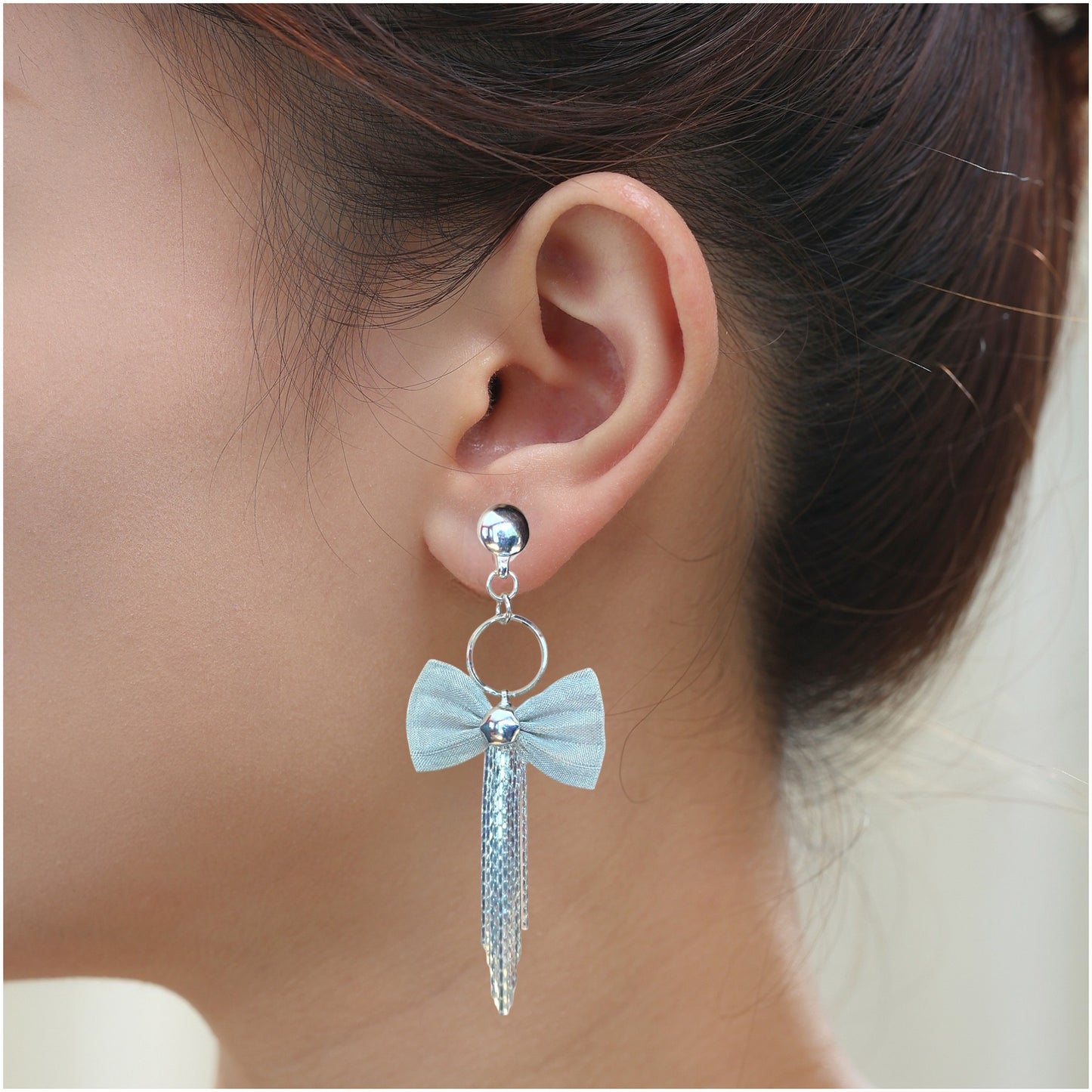 Silver chains and beautiful bow earring. Detachable earrings for a truly hypoallergenic jewellery on a young woman.