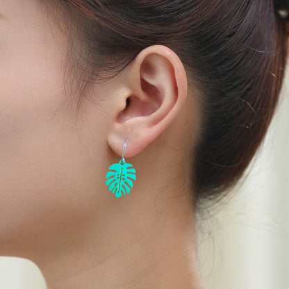 Monstera leaf earrings with a titanium hook on a white young woman