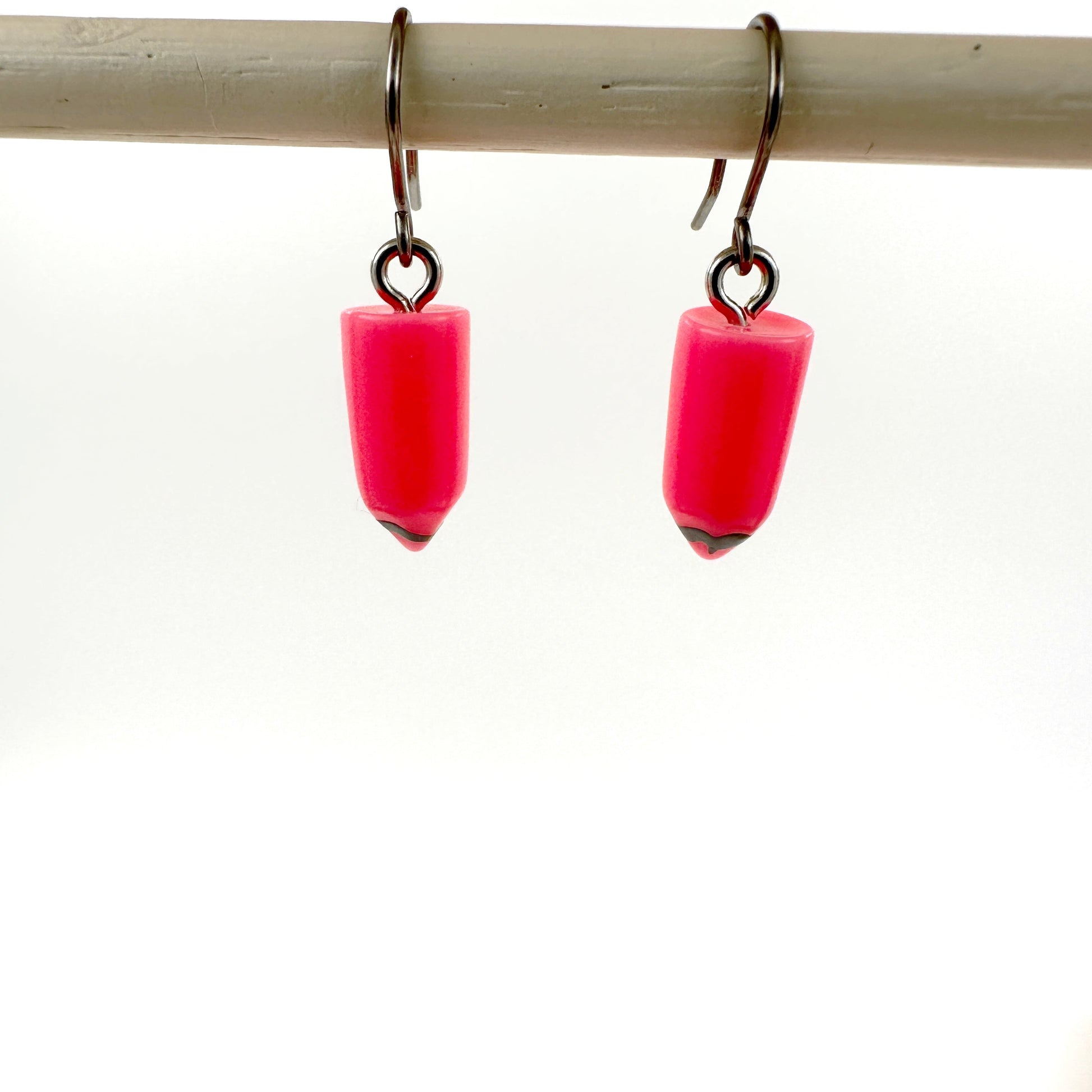 Pencil earrings with a titanium hook on a white background. pink