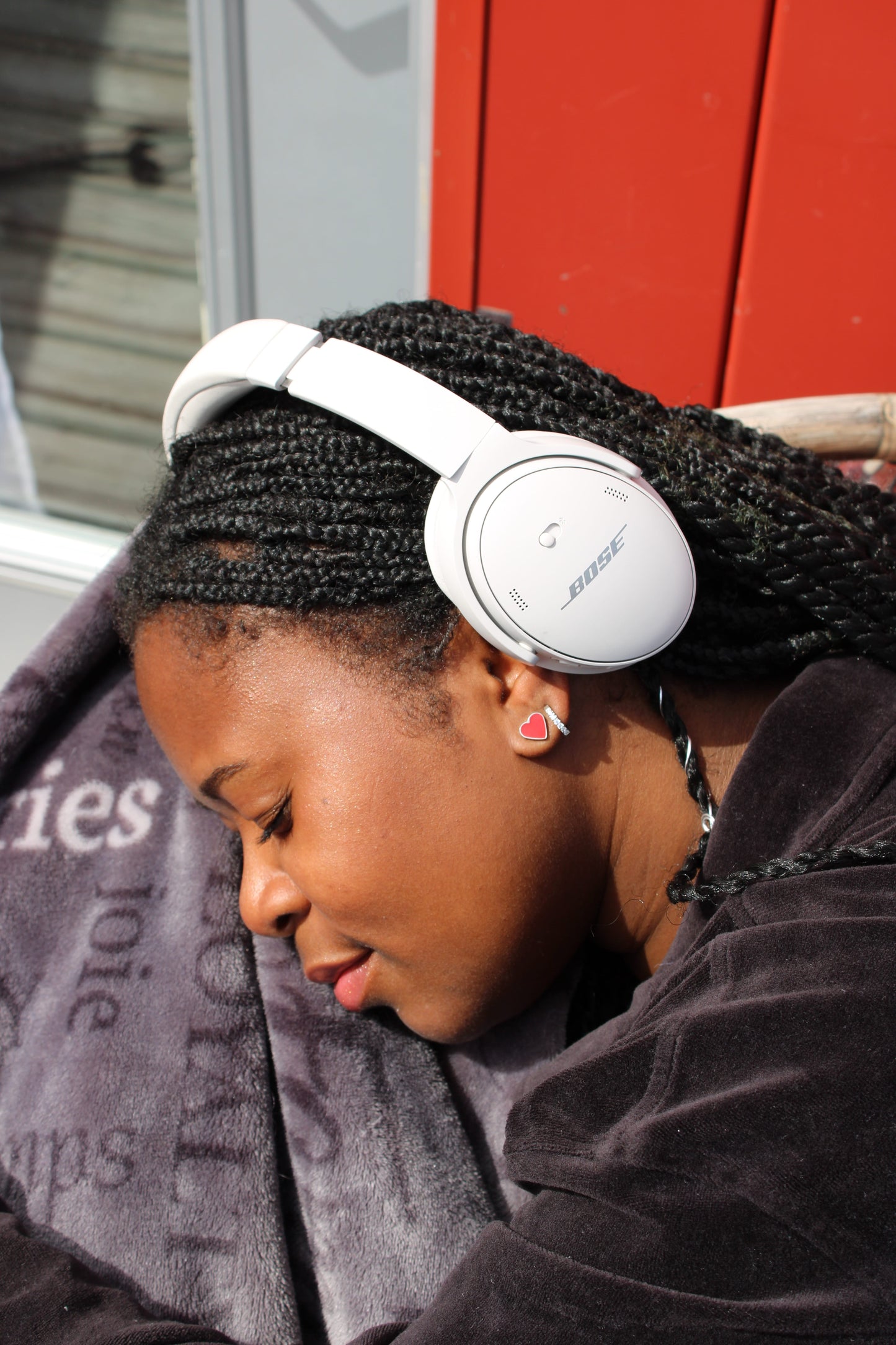 Red heart studs -solid titanium studs and backs- Feature a small and minimal design on a black woman. and headphones