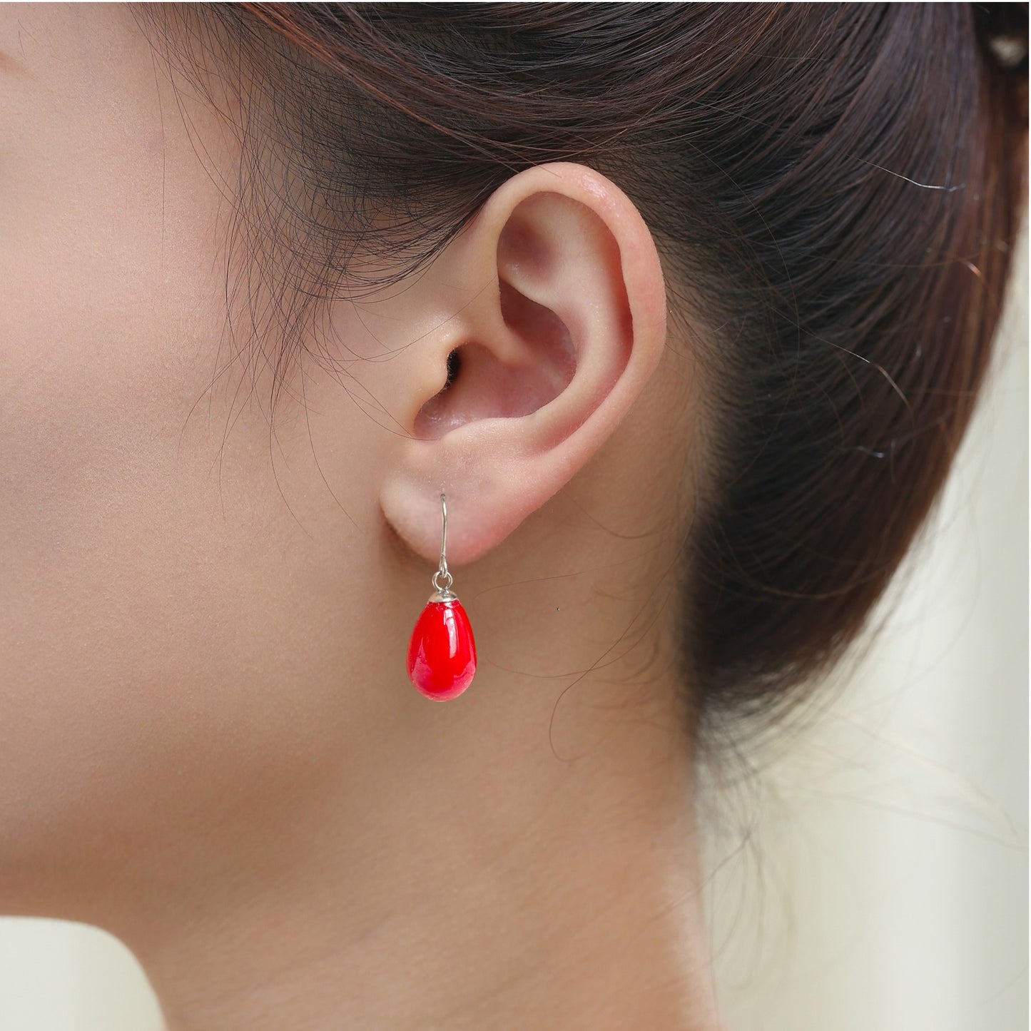 Red pearl earrings with a titanium hook on a white young woman