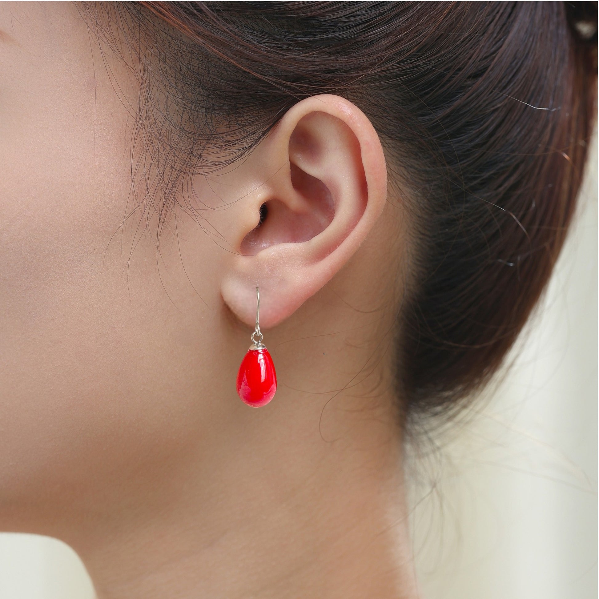 Red pearl earrings with a titanium hook on a white young woman