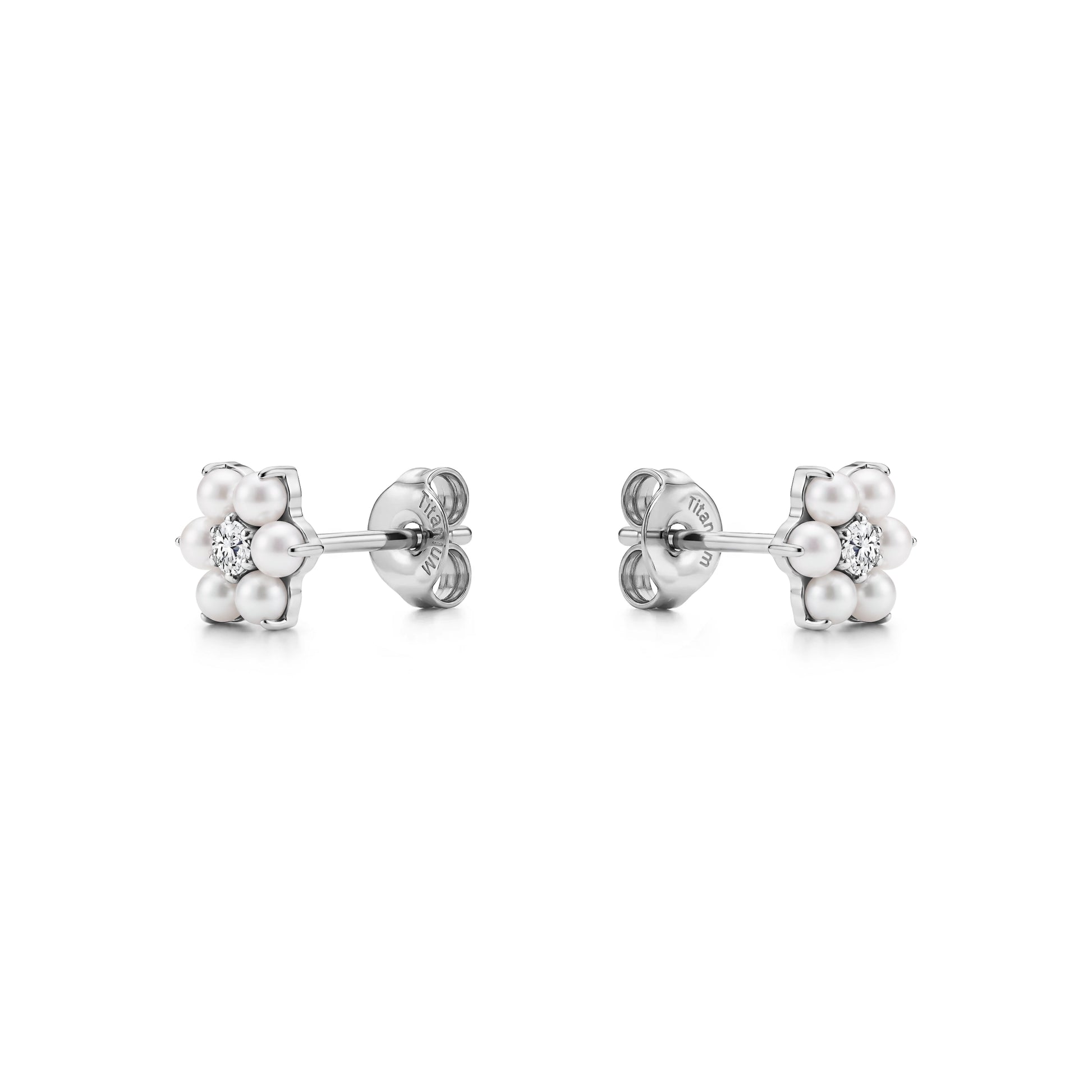 Pair of floral titanium stud earrings with pearls and a gem on a white background