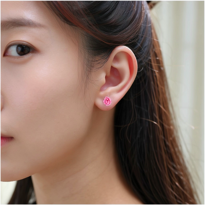 A close-up of a person's ear wearing a small pink rose-shaped titanium stud earring.