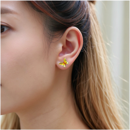 A close-up of a person's ear wearing a small butterfly-shaped titanium stud earring in shades of orange, yellow.