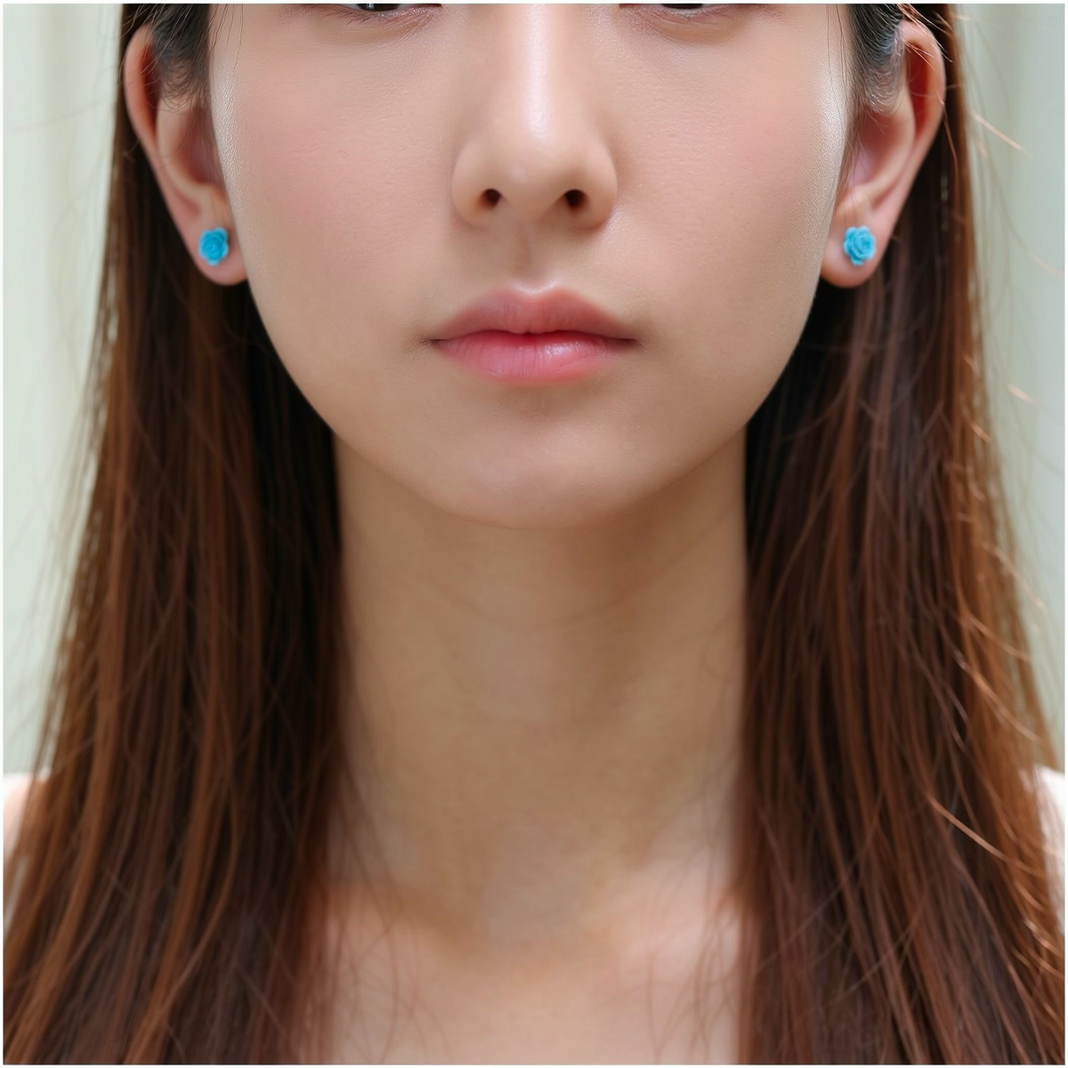 A close-up of a person's ear wearing a small bright blue rose-shaped titanium stud earring.
