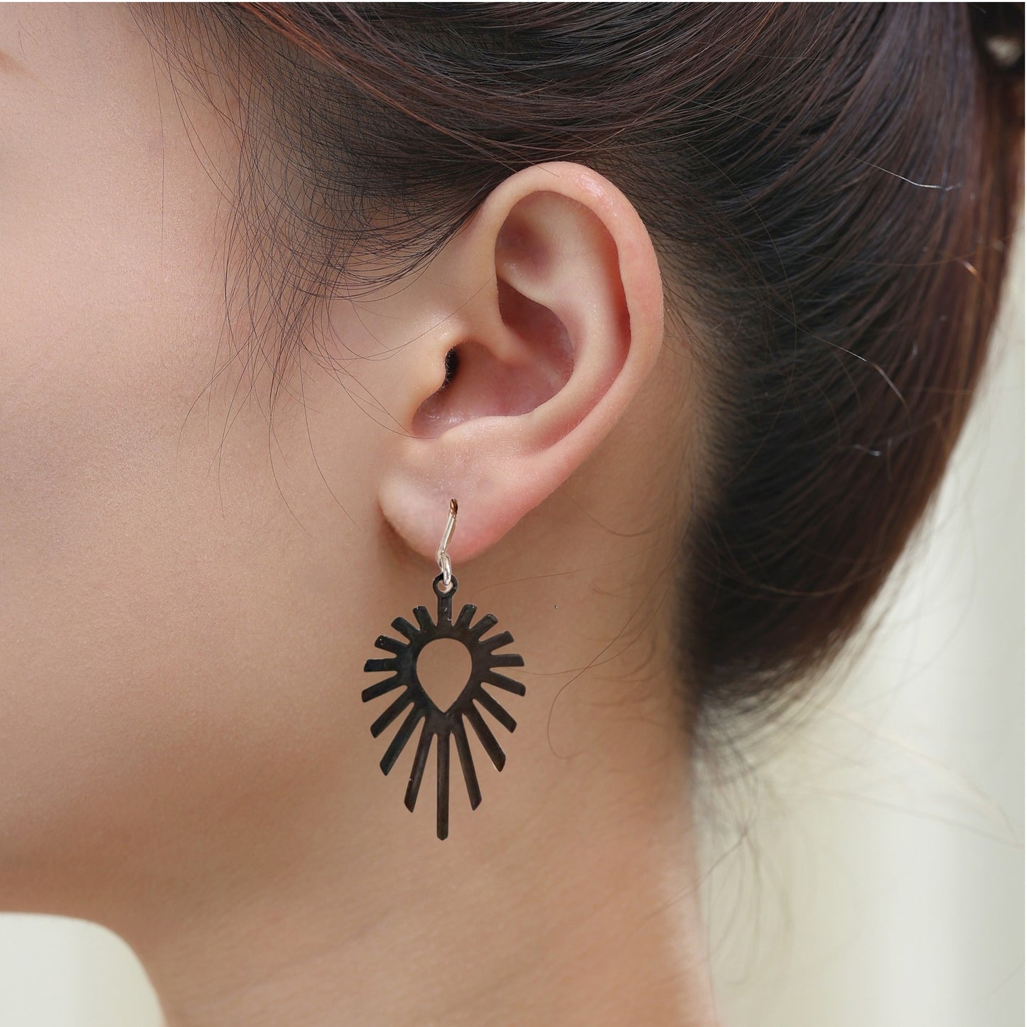 Shine teardrop black earrings with a titanium hook on a white young woman.