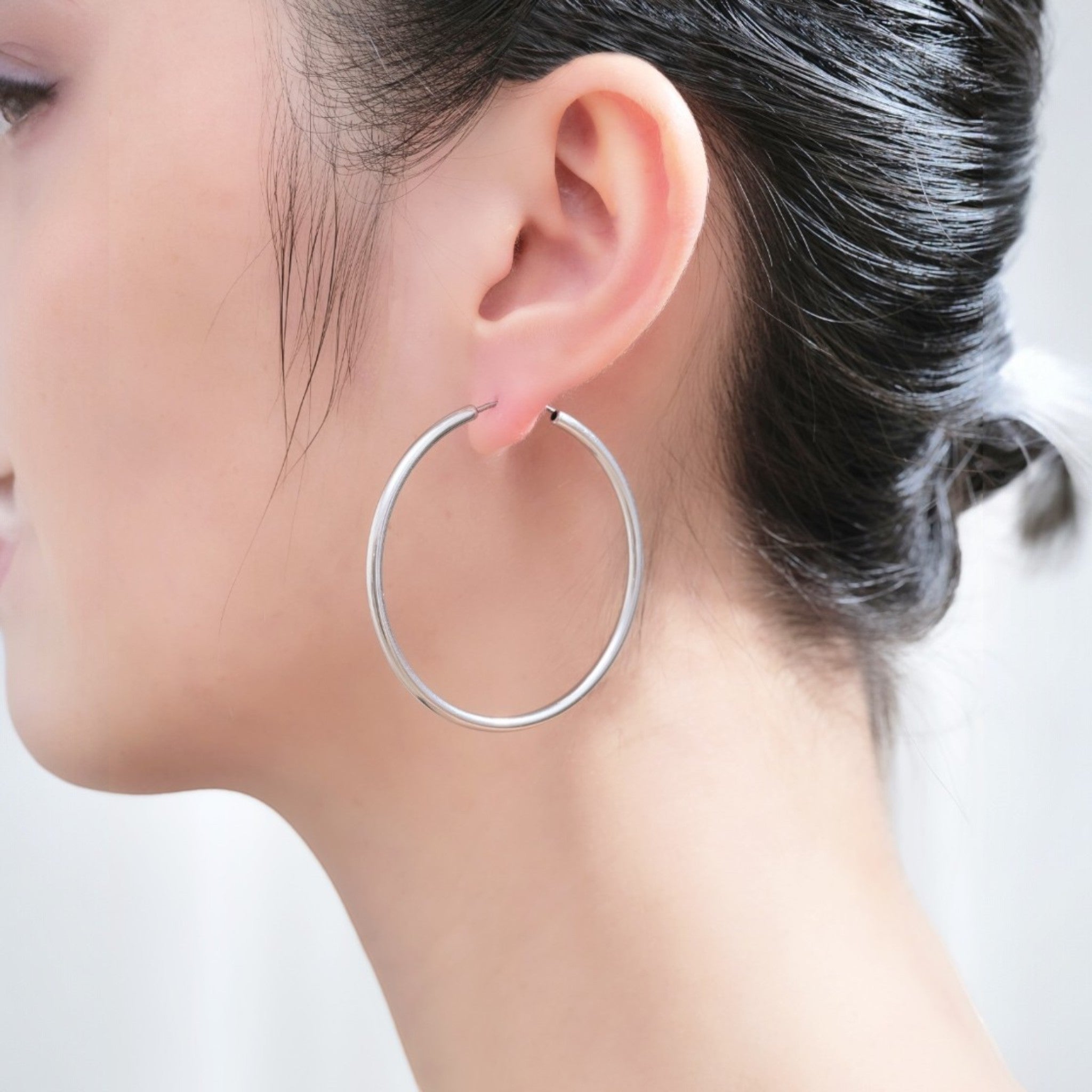 Silver Hoops on a white woman made with a titanium pin. 45mm titanium earring