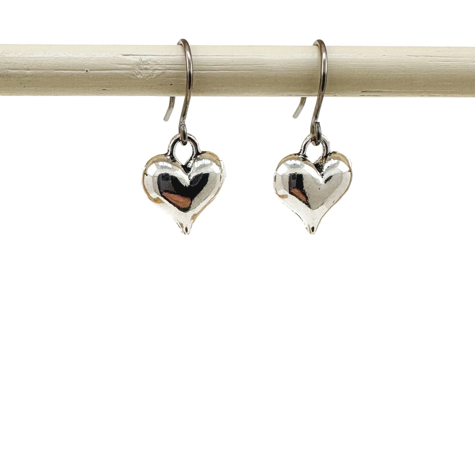 Silver heart earrings with a titanium hook on a white background